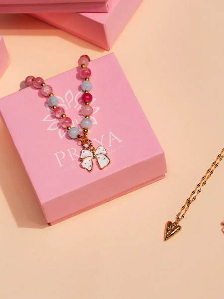 Jewelry set on pink Praya boxes with a gold chain and pink beads on a beige background